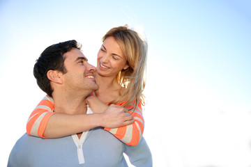 Obraz premium Man giving piggyback ride to girlfriend by the sea