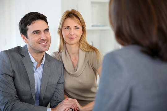 Cheerful couple receiving good news from advisor