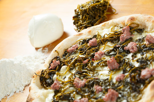 Italian Pizza, ingredients in the background on a wood table