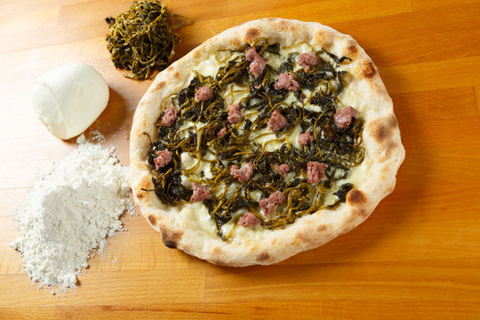 Italian Pizza, ingredients in background on a wood table