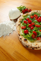 Italian Pizza, ingredients in background on a wood table