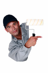 Tradesman holding a paint roller and pointing to a blank sign