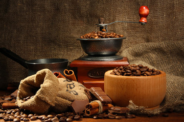 Coffee grinder, turk and cup of coffee on burlap background