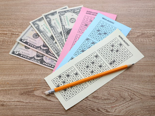 Lottery tickets with pencil and money, on wooden background