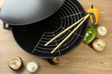 Fototapeta na wymiar Czarny pan wok i warzyw na stole w kuchni, z bliska