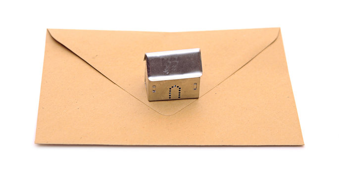metall house shaped object on brown envelope