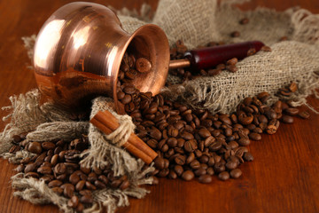Coffee pot with coffee beans on brown wooden background