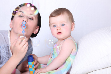 Mother sat with baby blowing bubbles