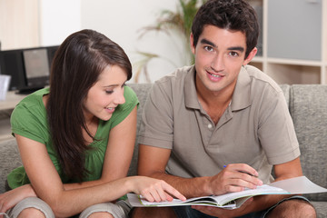 Fototapeta premium young couple at home skimming through catalogue