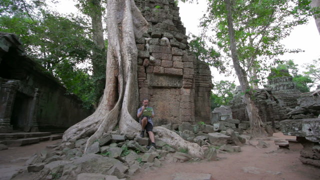 Visitor reading tourist information map in Ta Prohm temple
