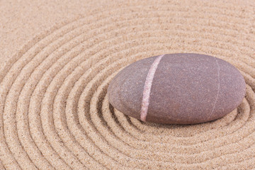 Pebble in a raked sand circle zen garden
