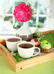 Cups of tea with flower and cakes