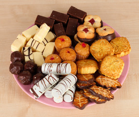Sweet cookies on plate on wooden background