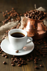 Cup of coffee and pot on wooden background