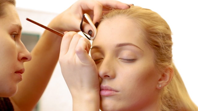 Makeup artist is applying makeup to model's eyebrows