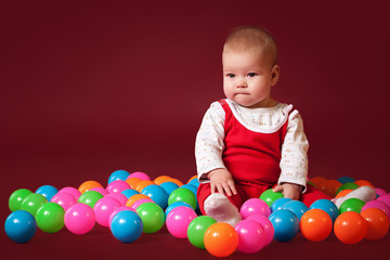 Fototapeta na wymiar little baby with balls on dark red background