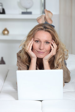 Woman lying on her stomach in front of a laptop computer