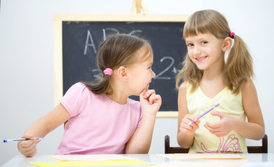 Little girls are writing using a pen