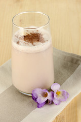 Glass of chocolate-cream cocktail on wooden table close-up