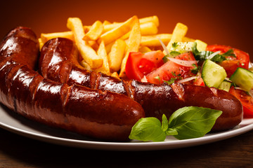 Grilled sausages, French fries and vegetables