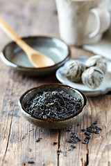 Green tea leaves and white tea balls on wooden background