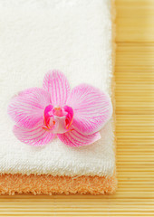 Stack of towels with pink orchid flower
