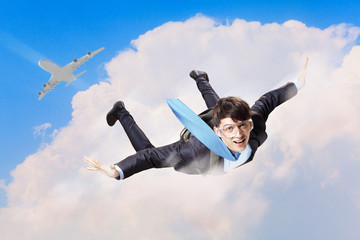 Young businessman flying with parachute on back