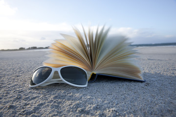 Buch und Sonnenbrille im Sand