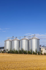 four silver silos in the field after the harvest