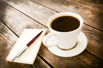 Cup of coffee and notebook next to it.