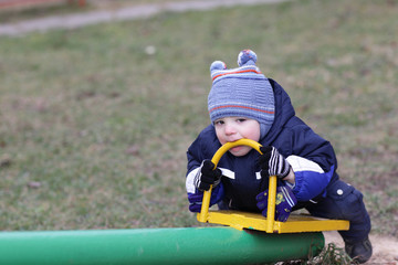 Toddler holding handle of seesaw by teeth