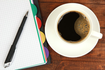 Cup of coffee on worktable covered with documents close up
