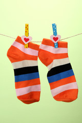 Colorful socks hanging on clothesline, on color background