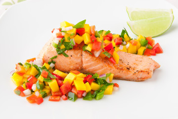 Salmon fillet with mango salsa on white plate.