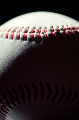 Vertical shot of a baseball ball over black background, macro
