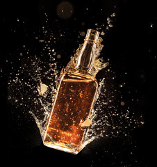 Concept of liquor splashing around bottle on black background