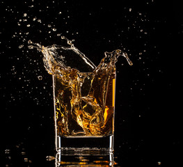  Glass of whiskey with splash, isolated on black background
