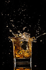  Glass of whiskey with splash, isolated on black background