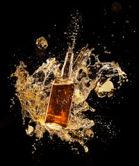Concept of liquor splashing around bottle on black background