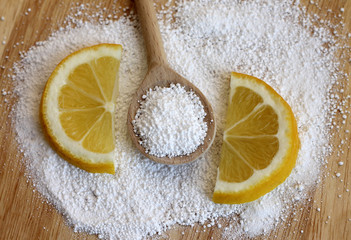 citric acid in wooden spoon with lemon, close-up