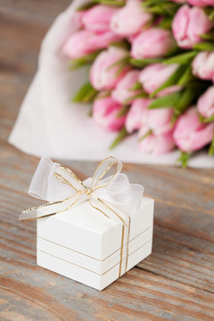 Gift box decorated with bows with tulips on the background