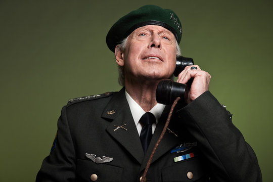 US military general wearing beret. Calling with phone. Studio po