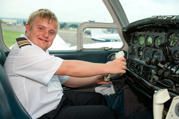 Portrait of young pilot with down syndrome in cabin.