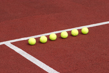 Line of six yellow tennis balls on court