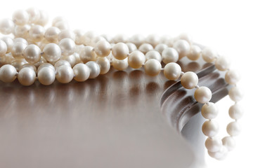 Pearl necklace on vintage wooden jewelry box against the light b