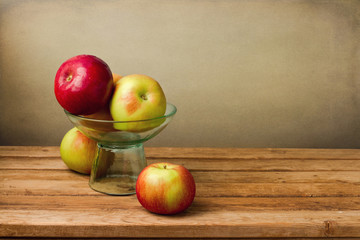 Fresh red apples in glass vase on wooden table
