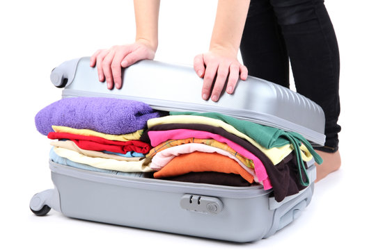 Girl tries to close the suitcase isolated on white