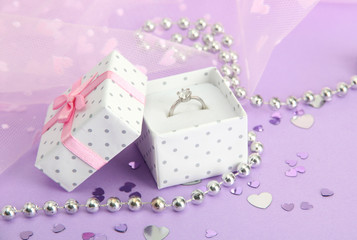 Beautiful box with wedding ring on purple background