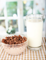 Delicious and healthy cereal in bowl with milk on table in room