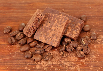 Chopped chocolate with cocoa, on wooden background